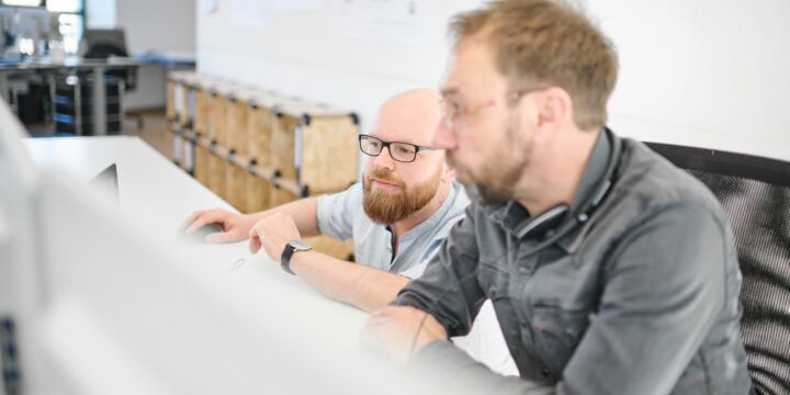 Mitarbeiter der Objektüberwachung und der Planung im Gespräch am Schreibtisch